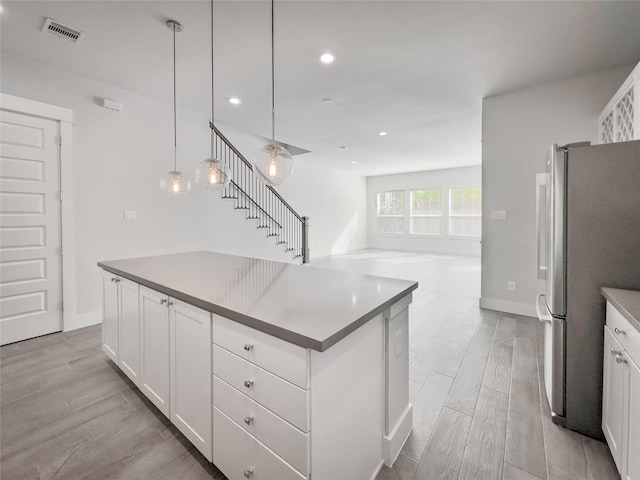 kitchen featuring visible vents, white cabinetry, freestanding refrigerator, and wood tiled floor