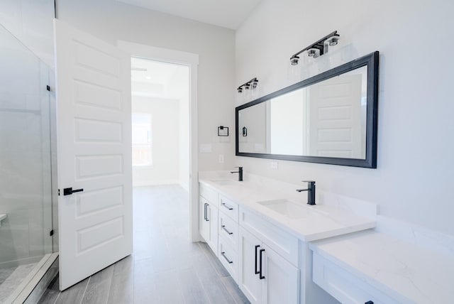 bathroom featuring double vanity, a shower stall, a sink, and wood finished floors