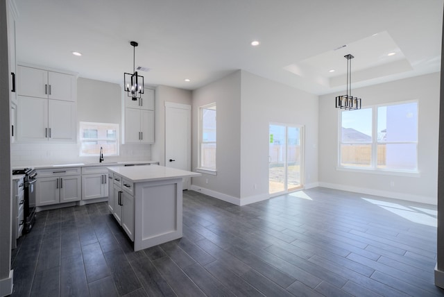 kitchen featuring black range with gas cooktop, dark wood-type flooring, a sink, light countertops, and tasteful backsplash