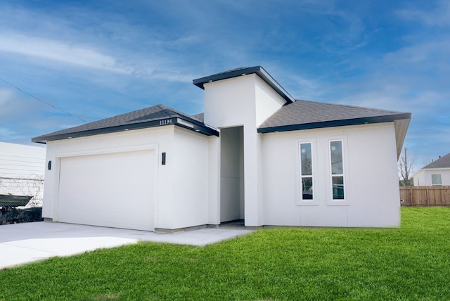 rear view of house with stucco siding, a lawn, an attached garage, fence, and driveway