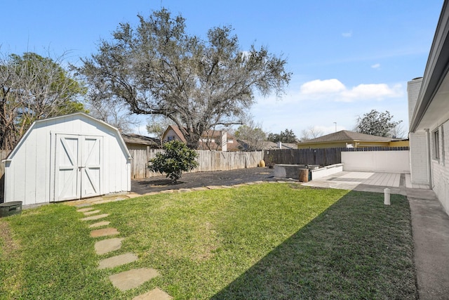 view of yard featuring a storage shed, a fenced backyard, a patio area, and an outbuilding