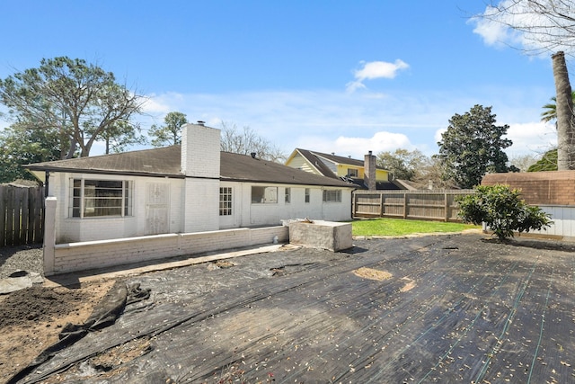 back of property with brick siding, a chimney, and a fenced backyard