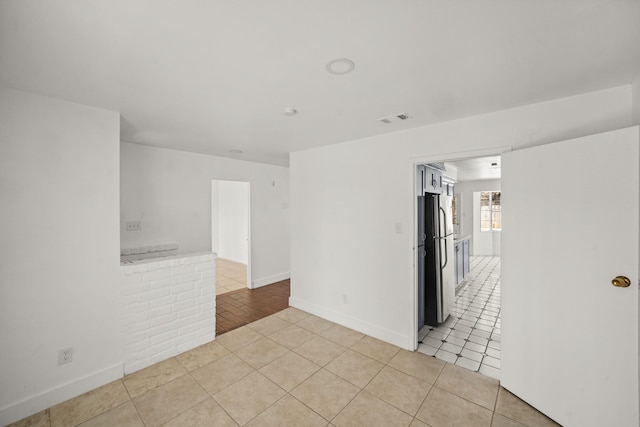 unfurnished room featuring light tile patterned flooring, visible vents, and baseboards