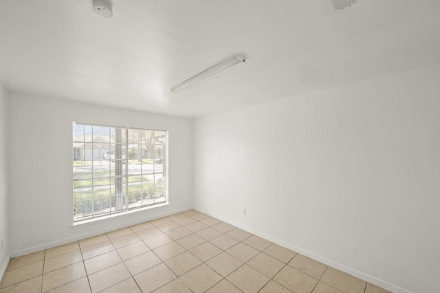 spare room with baseboards and light tile patterned floors