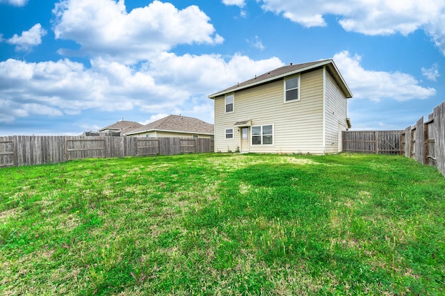 back of property with a lawn and a fenced backyard