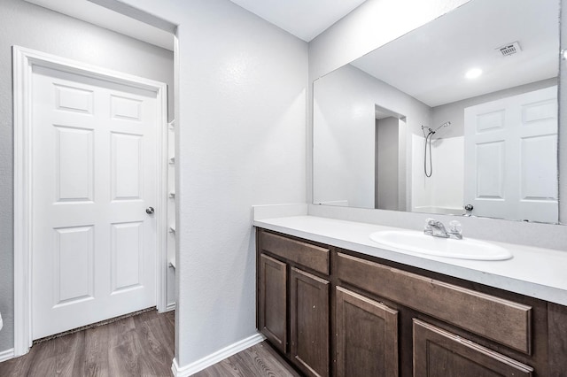 full bathroom with a shower, visible vents, vanity, wood finished floors, and baseboards