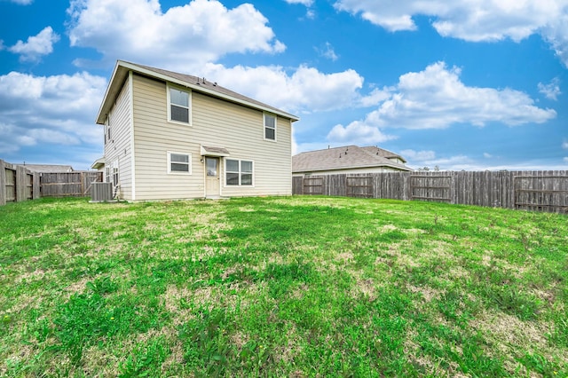 back of property with a fenced backyard, a lawn, and central air condition unit