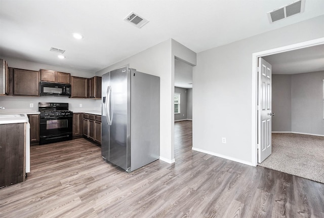 kitchen with light countertops, visible vents, a sink, and black appliances