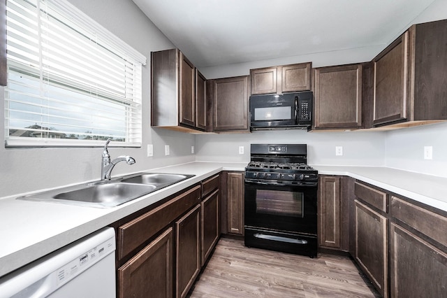 kitchen with dark brown cabinetry, a sink, light wood-style flooring, and black appliances