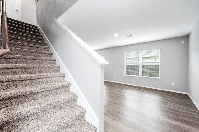 stairs with visible vents, baseboards, and wood finished floors