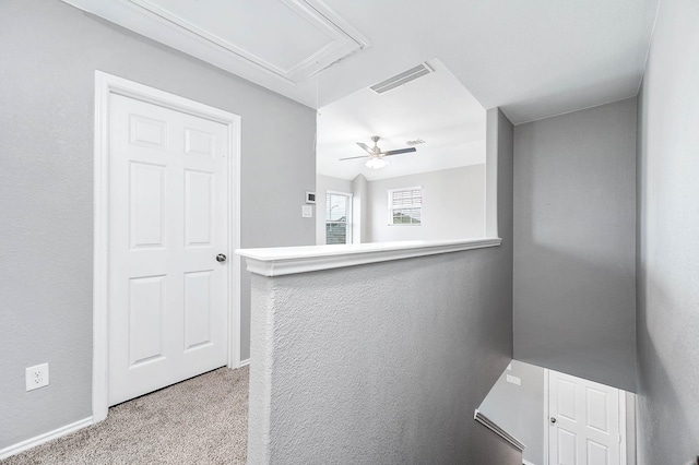 corridor featuring attic access, visible vents, and carpet flooring