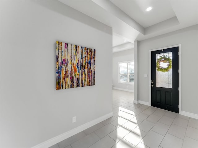 foyer entrance featuring recessed lighting, a raised ceiling, baseboards, and light tile patterned floors