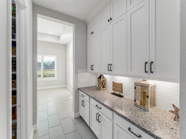 bar with light tile patterned floors, baseboards, a tray ceiling, backsplash, and recessed lighting