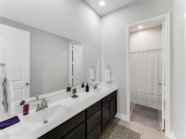 bathroom featuring tile patterned floors, a sink, a shower with shower curtain, and double vanity