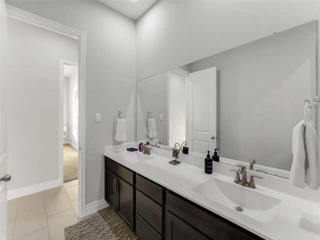 full bath featuring tile patterned floors, a sink, baseboards, and double vanity