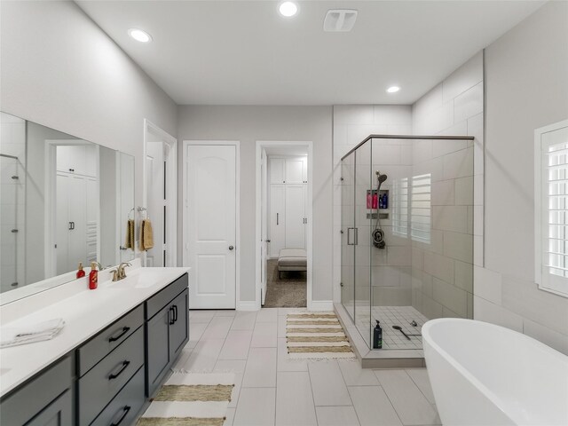 full bath with a stall shower, a freestanding tub, vanity, and recessed lighting