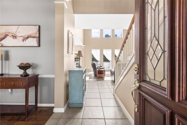 foyer entrance featuring light tile patterned floors, stairs, and baseboards