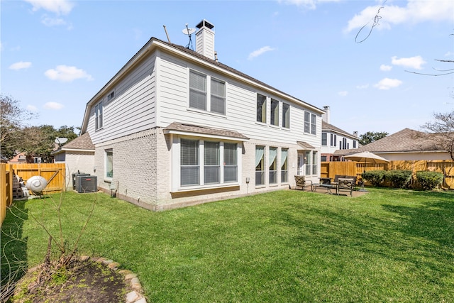 back of house featuring a lawn, a fenced backyard, a chimney, cooling unit, and a patio area