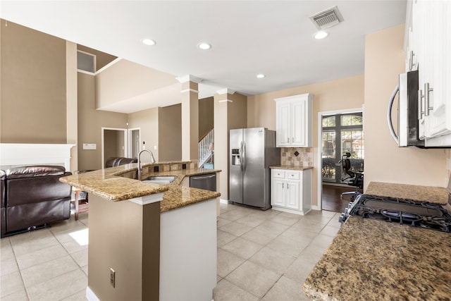 kitchen with visible vents, decorative backsplash, light stone countertops, stainless steel appliances, and a sink