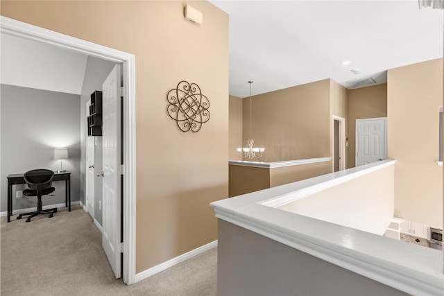 hallway with light carpet, baseboards, and a chandelier