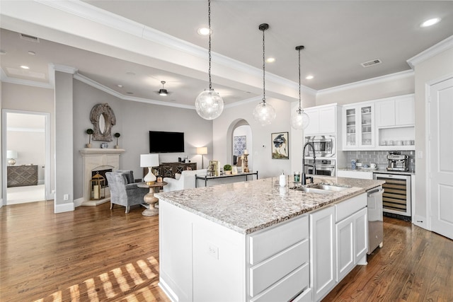 kitchen with a fireplace, appliances with stainless steel finishes, arched walkways, and dark wood finished floors