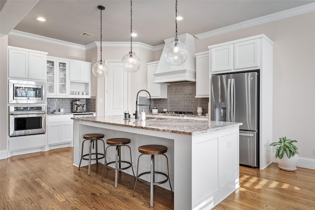 kitchen with visible vents, a breakfast bar area, stainless steel appliances, light wood-style floors, and a sink