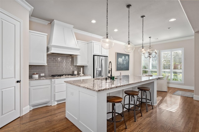 kitchen with tasteful backsplash, dark wood-style flooring, a kitchen island with sink, stainless steel appliances, and premium range hood