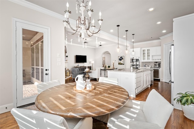 dining space with ornamental molding, arched walkways, and dark wood-style flooring