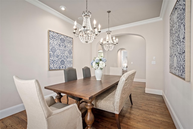 dining room featuring arched walkways, ornamental molding, wood finished floors, and baseboards