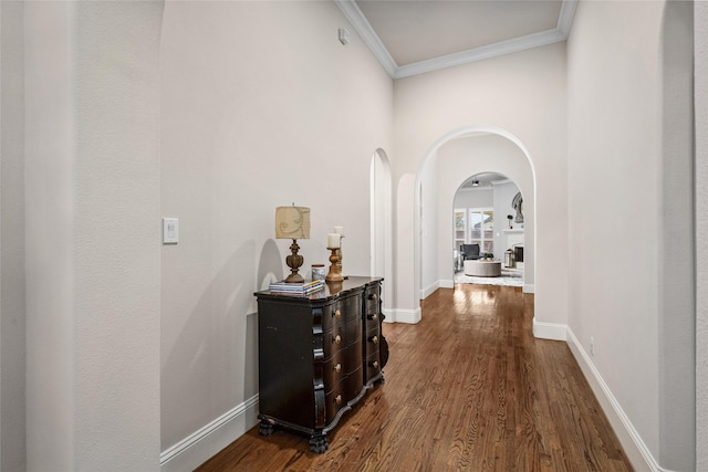 hallway featuring baseboards, ornamental molding, dark wood finished floors, and arched walkways