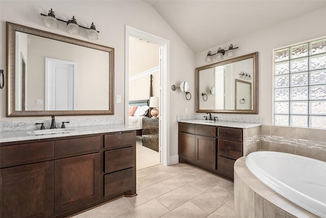 ensuite bathroom featuring lofted ceiling, a garden tub, two vanities, and a sink