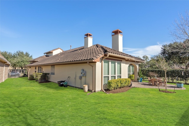 rear view of house featuring a tiled roof, fence, a yard, a patio area, and stucco siding