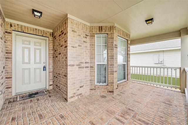 entrance to property with a porch and brick siding