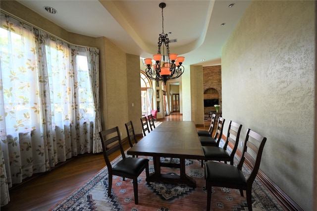 dining room with a raised ceiling, visible vents, a textured wall, an inviting chandelier, and wood finished floors