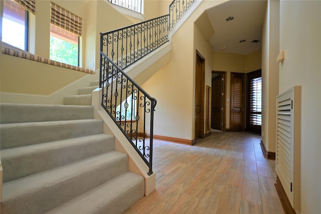 staircase featuring a high ceiling, wood finished floors, and baseboards