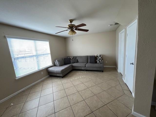 unfurnished living room featuring a ceiling fan, baseboards, and light tile patterned floors