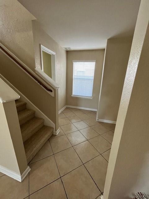 staircase with baseboards and tile patterned floors