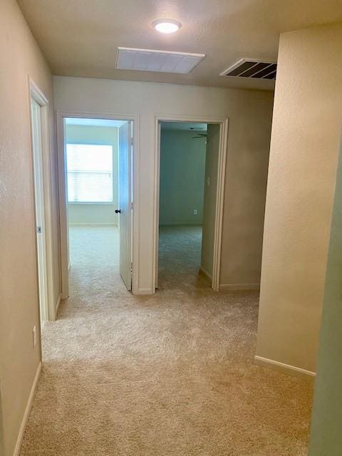 hall featuring carpet, visible vents, and baseboards