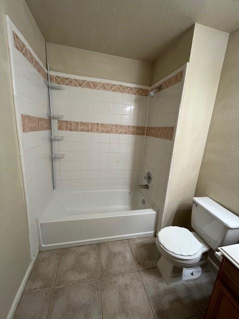 bathroom featuring toilet, washtub / shower combination, vanity, tile patterned flooring, and baseboards