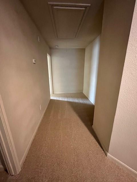 corridor featuring attic access, carpet, and baseboards