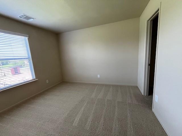 carpeted spare room featuring baseboards and visible vents