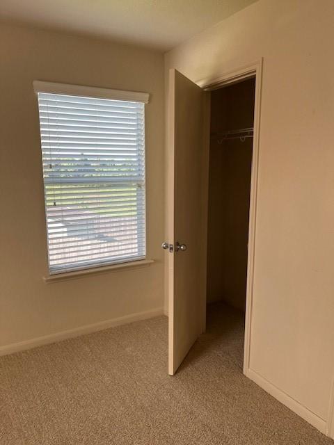 unfurnished bedroom with baseboards, a closet, and light colored carpet