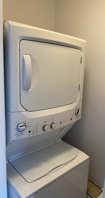 laundry room featuring stacked washer and clothes dryer, a textured wall, and laundry area