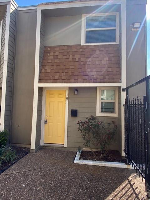 property entrance featuring a shingled roof and fence