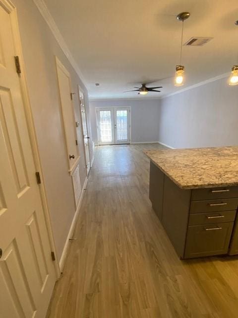 interior space with baseboards, light wood-style flooring, visible vents, and crown molding