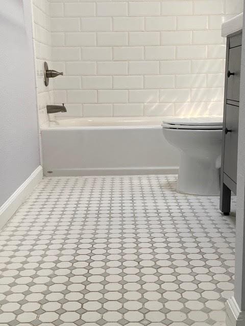 bathroom with shower / bathtub combination, toilet, and baseboards