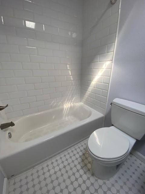 bathroom featuring toilet, shower / washtub combination, and tile patterned floors