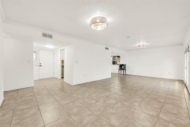 spare room featuring a textured ceiling, visible vents, and crown molding