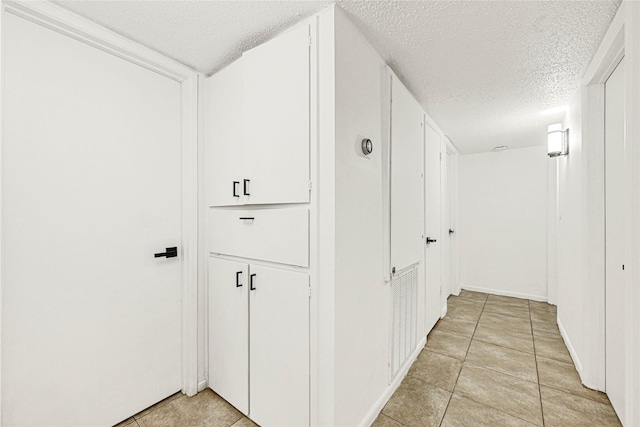 hallway featuring a textured ceiling and light tile patterned floors