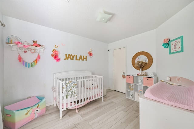 bedroom featuring a nursery area and wood finished floors